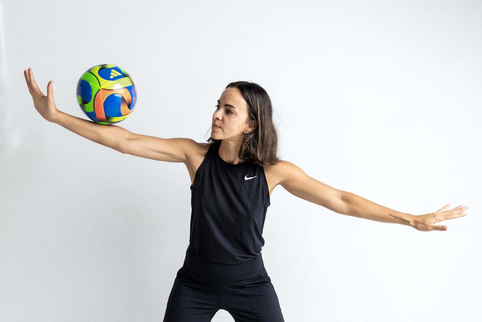 Coach Bianca balancing a football on one hand, arms outstretched